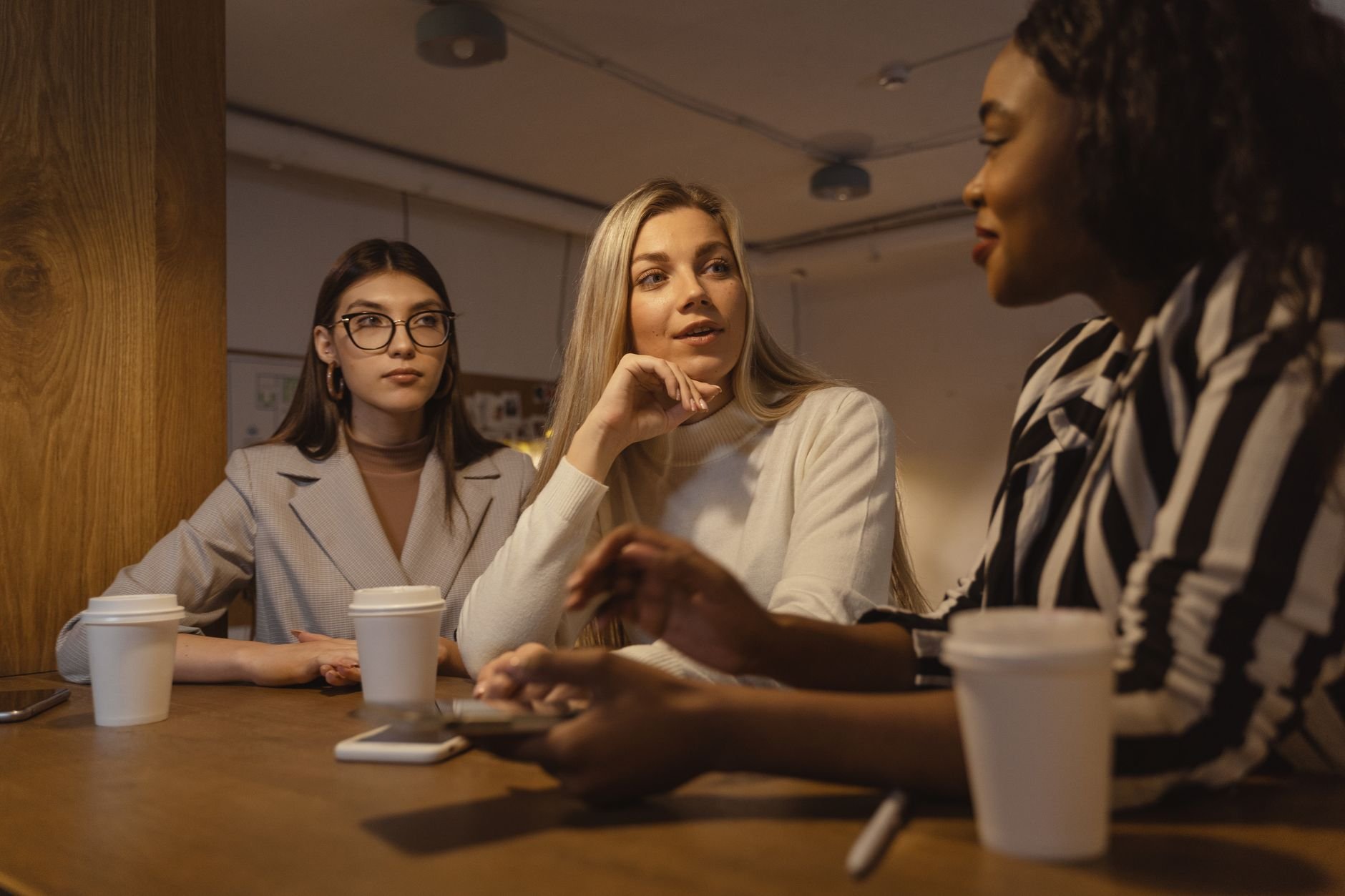 Three business owners engaged in a friendly discussion around a table — the kind of clear, simple conversation Brightly AI is built around